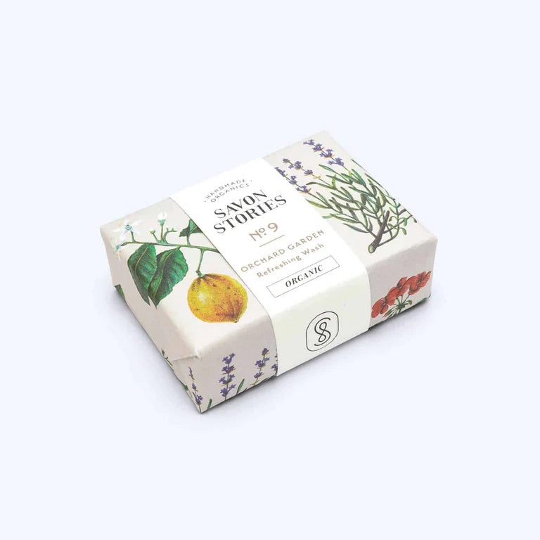 Rectangular bar of organic soap wrapped in paper printed with fruits and flowers with a cream sleeve handmade organics Savon Stories and words in French 